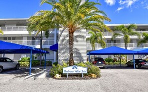 Letrero de Harbour Villa Club, con una palmera y toldos azules al frente.