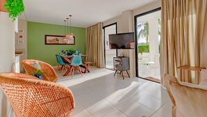 Una sala de estar moderna con comedor, televisor de pantalla plana y un amplio ventanal con cortinas.