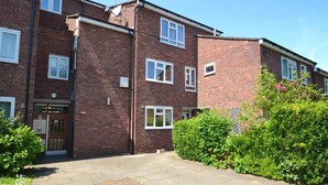 A multi-story brick apartment building with a front entrance, windows, and a satellite dish. - 1 Bed-sleeps 4-free Parking-15 Min to Putney (London)