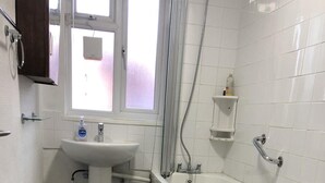 A bathroom with a white sink, a bathtub, a window, and a shower. - 1 Bed-sleeps 4-free Parking-15 Min to Putney (London)