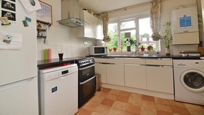 A compact kitchen with a dishwasher, stove, microwave, and washing machine. - 1 Bed-sleeps 4-free Parking-15 Min to Putney (London)