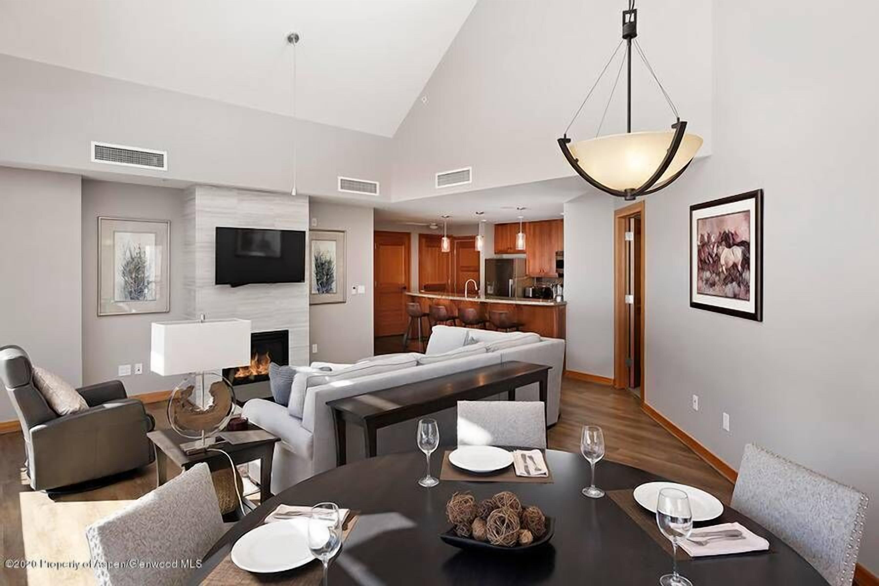 Una sala moderna con chimenea, un comedor con mesa redonda y una cocina al fondo.