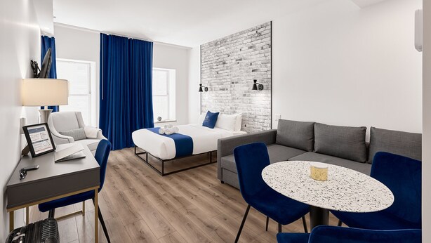 Ett modernt hotellrum med en säng, en soffa, ett matbord och ett skrivbord.