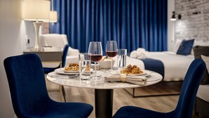 Ett bord dukat för två personer, med tallrikar med spaghetti, glas med vatten och rött vin, och en lampa i bakgrunden.