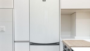 Une cuisine moderne avec des meubles blancs, un four encastré et un plan de travail en bois.