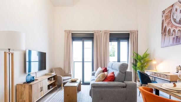 Un salon moderne comprenant un canapé, un téléviseur et un coin repas avec une table et des chaises.