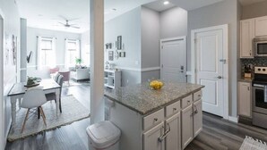 A modern kitchen with granite countertops, a built-in oven, and a dining area with a white table and chairs.