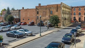 A street view with parked cars, a brick building, and a sign for '117 The Avenue Apartments'.
