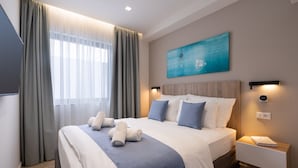 A modern hotel room with a large bed, a bedside table with a lamp, a painting on the wall, and a window with curtains. - Hestia - Ippokratous 35 (Athens)