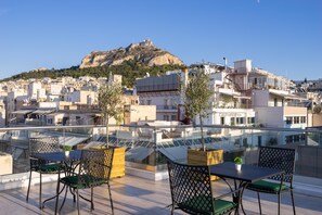 A rooftop terrace with a table and chairs, overlooking a cityscape with buildings and a hill. - Hestia - Ippokratous 35 (Athens)