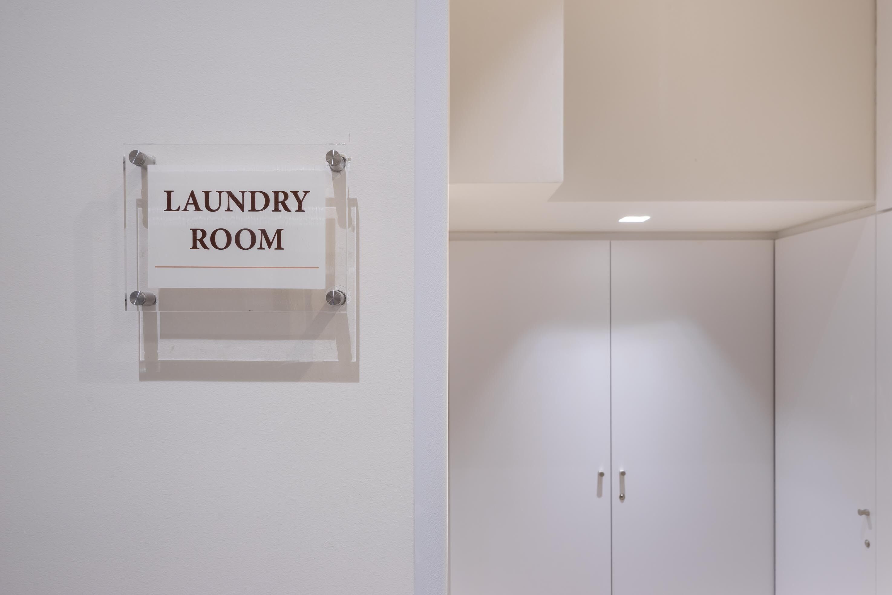 A sign indicating a laundry room, a white door, and a white wardrobe with two doors.