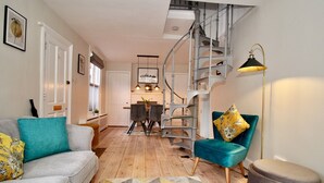 A modern living room with a staircase, a sofa, a chair, and a lamp. - A Character Cottage in Historical Canterbury - Pass the Keys (Canterbury)