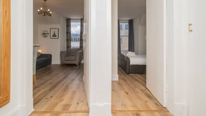 A room with a bed, a chair, a chandelier, and a view through a window. - Cosy Flat in Historic Old Town - Pass the Keys (Edinburgh)