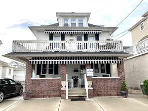 A two-story building with a balcony, a 'For Sale' sign, and a brick facade. - Third floor apartment with private entrance.. (North Wildwood)