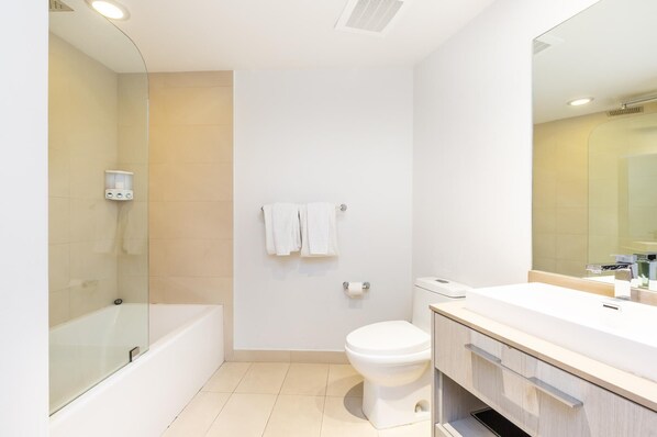 A modern bathroom with a bathtub, toilet, and vanity.
