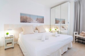 A hotel room with a large bed, bedside tables, a mirror, and a view of the beach.