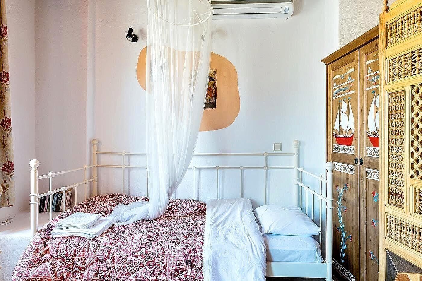 A bedroom with a bed, a wardrobe, and a mosquito net.
