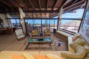 Relax in a spacious lounge area with a high ceiling, sofa, armchairs, and ocean views.
