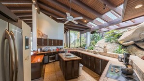 Una cocina moderna con una isla integrada, un muro decorativo de piedra y un ventilador de techo.
