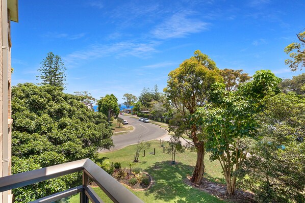A residential area with a curved road, lush greenery, and a clear blue sky.