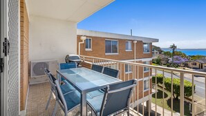 A balcony with a table and chairs, overlooking a residential area and the sea. - Yarramundi a Nelson Bay Apartment Near Beach (Nelson Bay)