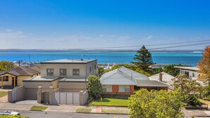 A residential area with houses, a clear blue sky, and a view of the sea. - Yarramundi a Nelson Bay Apartment Near Beach (Nelson Bay)