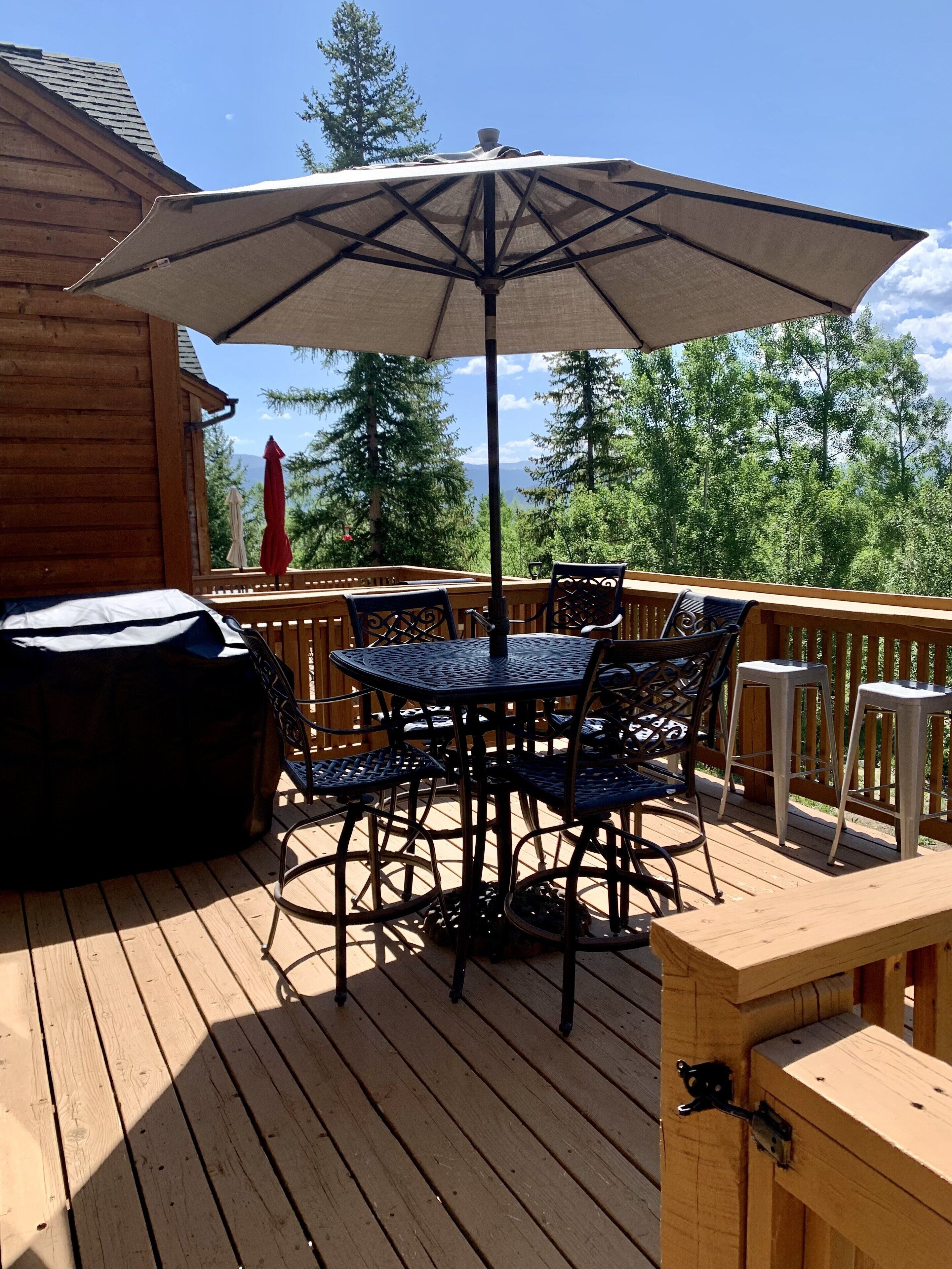 Une terrasse en bois avec une table et des chaises, un parasol et un jacuzzi.