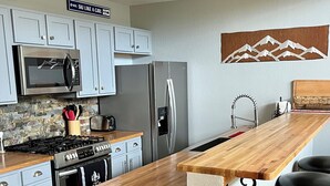 Eine moderne Küche mit einer Holzinsel, Edelstahlgeräten und einer Stein-Spritzschutzwand.