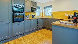 A modern kitchen with grey cabinets, a wooden floor, and a window providing natural light. - 3 bedroom accommodation in Duror (Duror)