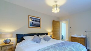A bedroom with a bed, bedside tables, a lamp, a framed picture, and a wardrobe. - 3 bedroom accommodation in Duror (Duror)
