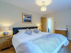 A bedroom with a bed, bedside tables, a lamp, a framed picture, and a wardrobe.