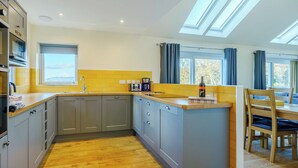 A modern kitchen with a built-in island, a window, and a skylight. - 3 bedroom accommodation in Duror (Duror)