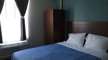 A hotel room with a bed, a wardrobe, and an air conditioning unit.