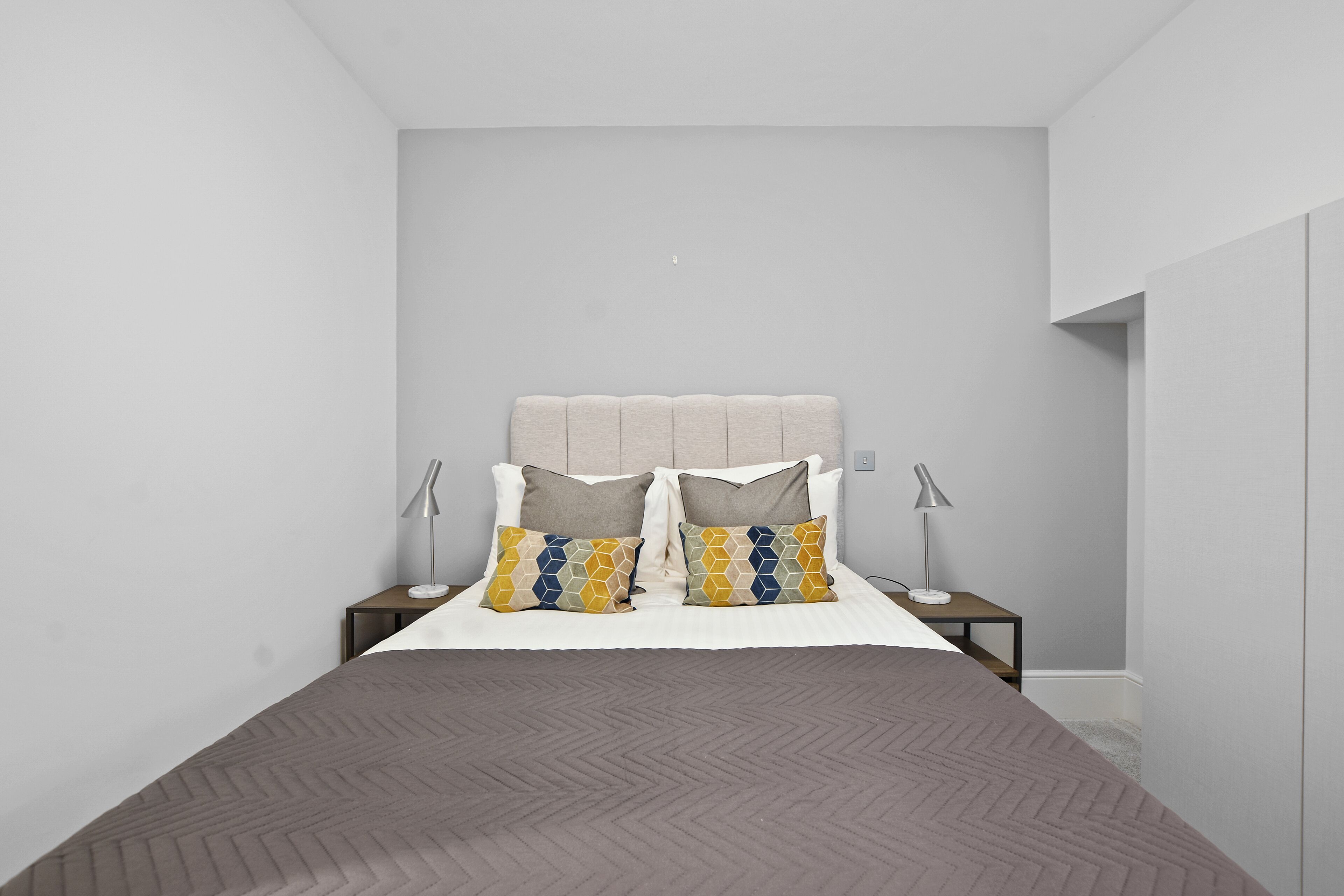 Un dormitorio moderno con una cama grande, dos mesitas de noche y un cabecero.
