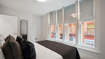 A hotel room with a large bed, a mirror, and a view of the outside.
