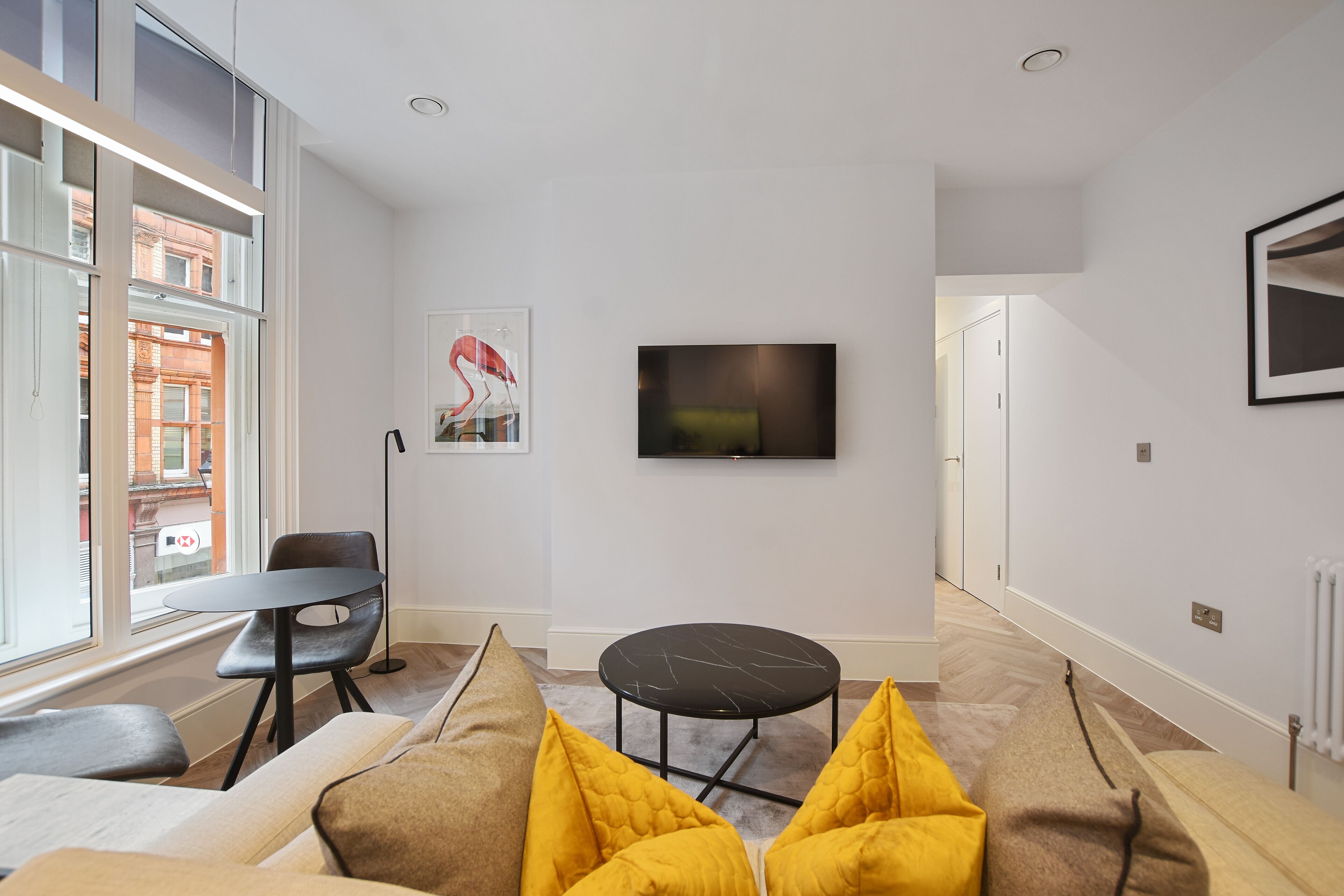 A modern living room with a sofa, a round coffee table, and a television mounted on the wall.