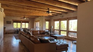 A spacious living area with a large L-shaped sofa, a dining table, and a ceiling fan. - Luxury Million Dollar Mountain Views: Golf Course Community across Ski Area!  (Angel Fire)