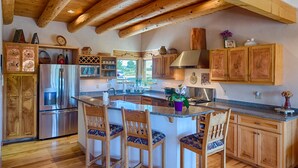A spacious kitchen with wooden cabinets, a stainless steel refrigerator, and a large island with bar stools. - Luxury Million Dollar Mountain Views: Golf Course Community across Ski Area!  (Angel Fire)