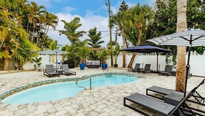 A pool area with lounge chairs, umbrellas, and palm trees. - Vintage Cottage from 1936 across street from Beach  and  Heated Pool (Siesta Key)