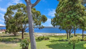 A coastal landscape with trees, a grassy area, and a view of the sea.