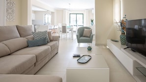 Relax in this stylish living room with a beige sofa, light grey armchair, and flat-screen TV.