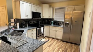 A compact kitchen with white cabinets, a stainless steel refrigerator, a microwave, and a stove. - 3BD-2BA 2nd flr Dreamy Rehoboth Beach Getaway (Rehoboth Beach)