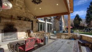 Ein Kamin aus Stein, Sitzgelegenheiten im Freien und eine überdachte Terrasse.