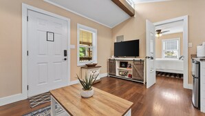 A spacious living room with hardwood floors, a wooden coffee table, a TV, and a dining area with a rug.
