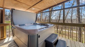 A hot tub on a wooden deck with a view of trees.