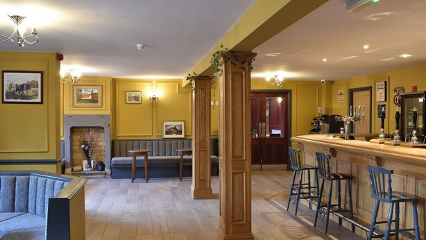 A bar area with stools, a fireplace, and framed pictures on the wall.