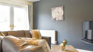 A living room with a sofa, a coffee table, a TV, and a painting on the wall.