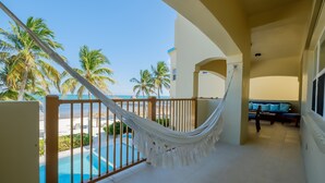 Ein Balkon mit Hängematte, Pool und Blick auf Strand und Palmen.