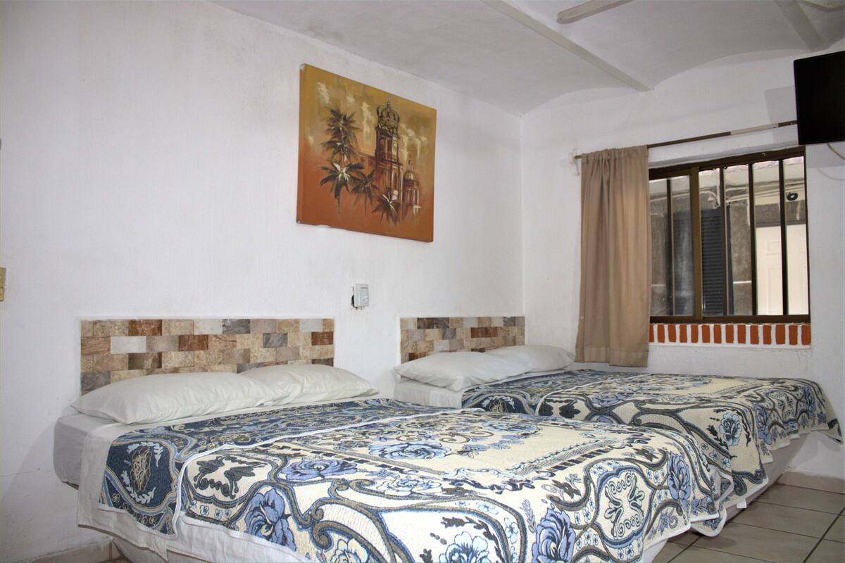 A room with two beds, a painting on the wall, and a window with curtains.