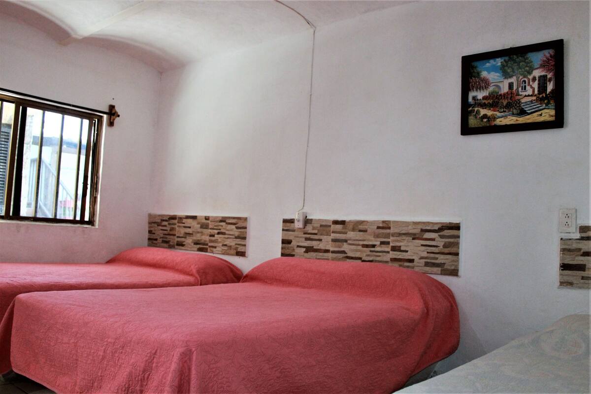 A room with two beds, a window, and a painting on the wall.